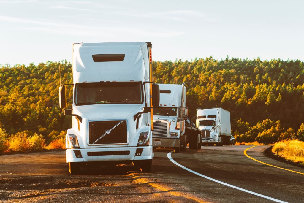 Trois semi-remorques circulant sur une autoroute à travers un paysage boisé en Arizona.